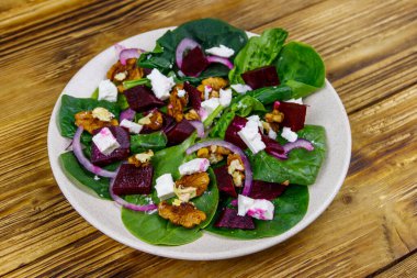 Haşlanmış pancar, peynir, ceviz ve ahşap masada kırmızı soğanlı ıspanak salatası. Sağlıklı vejetaryen yemekleri