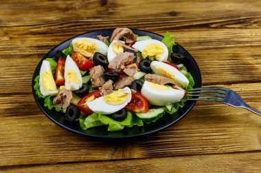 Marul, siyah zeytin, yumurta ve ahşap masada taze sebzeli lezzetli ton balığı salatası.