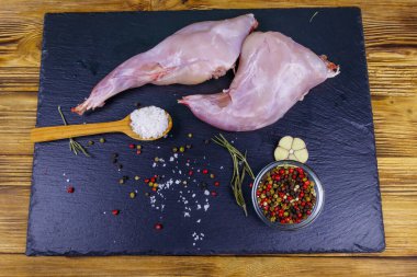 Çiğ tavşan bacağı ve üzerinde baharat olan tahta tahta tahta kesme tahtası. Üst görünüm