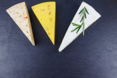 Siyah tahta zemin üzerinde çeşitli peynir türleri. Üst görünüm