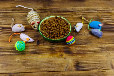 Kedi ve kase için tahta arka planda ev hayvanı yiyeceği olan oyuncaklar. Hayvan bakımı konsepti