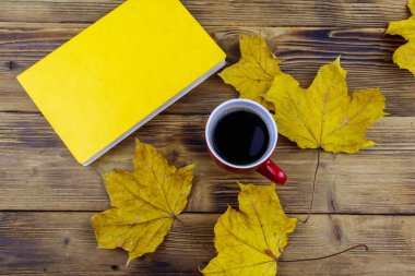 Bir fincan kahve, kitap ve sonbahar akçaağaç yaprakları ahşap masada. Üst Manzara. Sonbahar rahat konsepti