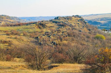 Sonbaharda kayalık tepeler, çayırlar ve ağaçların manzarası