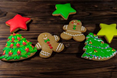 Noel ağacı şeklindeki lezzetli Noel kurabiyeleri, zencefilli kurabiye adamlar ve tahta masadaki yıldızlar.