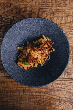 Tahta arka planda deniz ürünleri ve sebzeli spagetti.