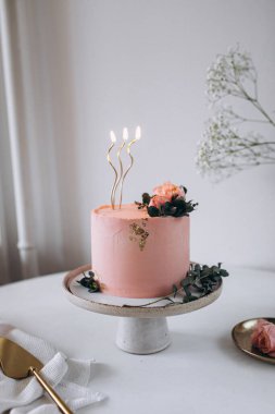 Masadaki pembe çiçeklerle süslenmiş pasta..