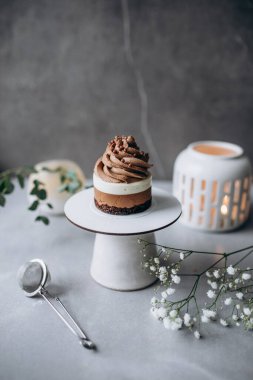 Kremalı lezzetli bir pastanın dikey yakın çekimi ve masada bir fincan kahve.