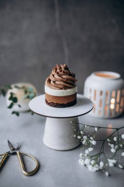 Bir fincan kahveli kek ve kaşıklı beyaz bir tabakta çiçek. Tatlı, tatlı ve tatlı konsepti.