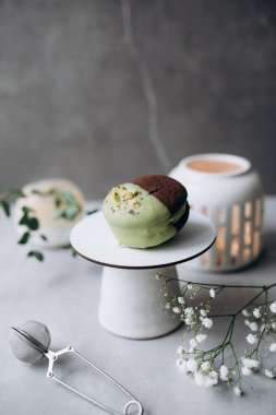 Kremalı çikolatalı kek ve beyaz masada yeşil çay.