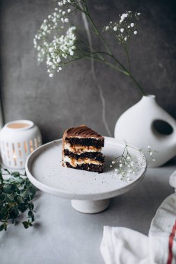 Bir dilim kiraz çiçeği ve bir fincan kahveyle bir parça kekin dikey fotoğrafı.