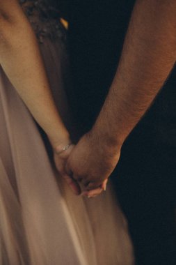 Gelin damadı gelinliğiyle tutuyor.