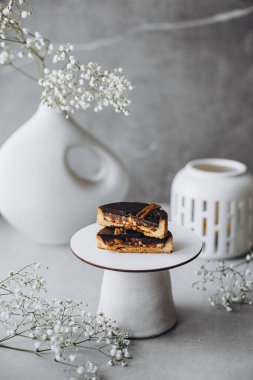 Çikolata jöleli pasta ve açık ahşap bir masada bir fincan çayla süslenmiş bir tabak seçici bir odak..