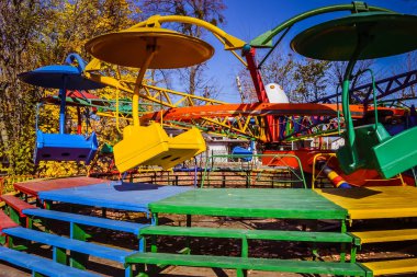 Sonbahar parkında eski Sovyet gezileri. Şemsiyeli atlıkarıncaların ve zincirli atlıkarıncaların renkleri farklı renklerdedir. Ukrayna.