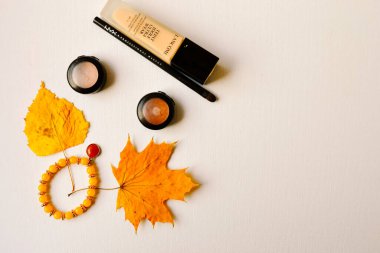 Hove, İngiltere, 03 / 11 / 2019. Açıklama: 'Lancome' şirketinin temel düzeni, 'aksesuar' bileziği, sarı küpeler, Nyx 'ten gölgeler ve göz kalemi ve sarı kuru yapraklar..