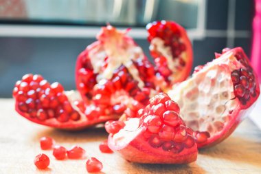 Red pomegranate torn into several pieces with berries falling nearby clipart