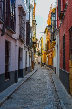 28.05.2023, Seville, İspanya: Dükkanlar, kafeler, restoranlar ve hediyelik eşya dükkanları ve renkli evleri ile Sevilla 'nın dar sokakları