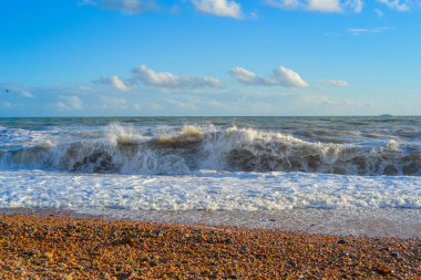 Gün batımında küçük bir fırtına, beyaz köpüklü yüksek dalgalar.