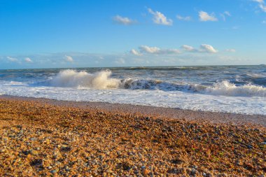 Gün batımında küçük bir fırtına, beyaz köpüklü yüksek dalgalar.