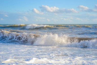 Gün batımında küçük bir fırtına, beyaz köpüklü yüksek dalgalar.