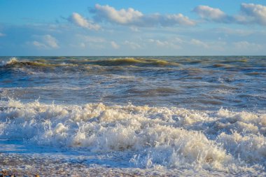 Gün batımında küçük bir fırtına, beyaz köpüklü yüksek dalgalar.