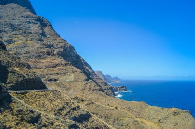 Gran Canaria adasının kuzeyindeki kayalar. Yol kayalıklardan geçer, okyanus görünür.