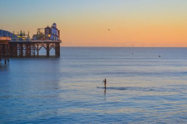 İngiltere, Brighton, 11.1.2025: gün batımında denizde bir sörf tahtasında adam