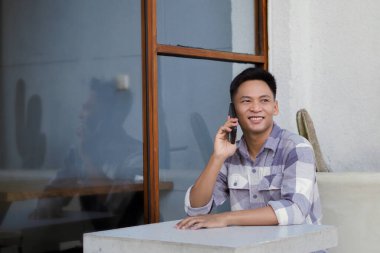 Telefonda konuşan, yukarı bakan, soldan bakan, kafede oturan bir adamın resmi.