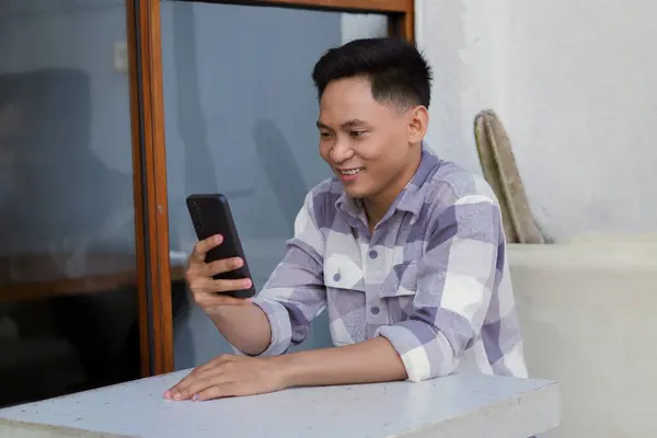 Young Asian Man Holding Cellphone Sitting Cafe Viewed Left Side — Stock Photo, Image