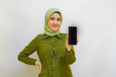 Mutlu Asyalı kadın reklam konsepti için telefonunu tutuyor. Yeşil kıyafet tesettür kadın konsepti