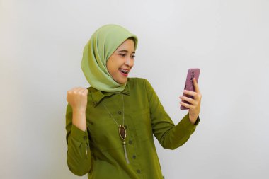 Mutlu Asyalı kadın reklam konsepti için telefonunu tutuyor. Yeşil kıyafet tesettür kadın konsepti