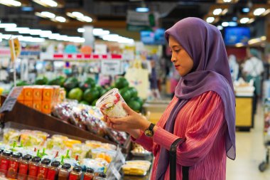 Markette ürünlere bakan mutlu Asyalı kadın. Müşteriler marketten yiyecek alıyor..