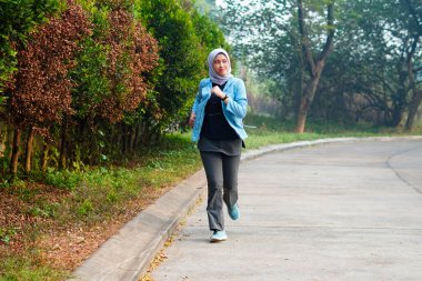 Mutlu ince başörtüsü giyen kadın gün doğumunda koşuyor. Genç, güzel Asyalı kadın dışarıda koşuyor. Sabahları egzersiz yapmak için. Sağlıklı ve aktif yaşam tarzı kavramı.