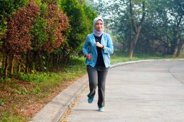 Mutlu ince başörtüsü giyen kadın gün doğumunda koşuyor. Genç, güzel Asyalı kadın dışarıda koşuyor. Sabahları egzersiz yapmak için. Sağlıklı ve aktif yaşam tarzı kavramı.