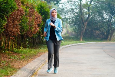 Mutlu ince başörtüsü giyen kadın gün doğumunda koşuyor. Genç, güzel Asyalı kadın dışarıda koşuyor. Sabahları egzersiz yapmak için. Sağlıklı ve aktif yaşam tarzı kavramı.