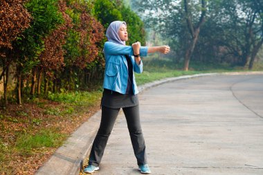 Güzel Müslüman kadın sabahları dışarıda çalışıyor. Alıştırma yaparak ısınan tesettürlü bir kadın..