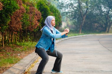 Güzel Müslüman kadın sabahları dışarıda çalışıyor. Alıştırma yaparak ısınan tesettürlü bir kadın..