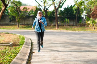 Mutlu ince başörtüsü giyen kadın gün doğumunda koşuyor. Genç, güzel Asyalı kadın dışarıda koşuyor. Sabahları egzersiz yapmak için. Sağlıklı ve aktif yaşam tarzı kavramı.