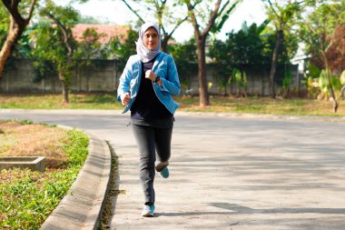 Mutlu ince başörtüsü giyen kadın gün doğumunda koşuyor. Genç, güzel Asyalı kadın dışarıda koşuyor. Sabahları egzersiz yapmak için. Sağlıklı ve aktif yaşam tarzı kavramı.
