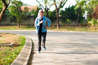 Mutlu ince başörtüsü giyen kadın gün doğumunda koşuyor. Genç, güzel Asyalı kadın dışarıda koşuyor. Sabahları egzersiz yapmak için. Sağlıklı ve aktif yaşam tarzı kavramı.