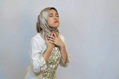 Endonezyalı Müslüman Kadın Ramazan ayında Beyaz Arkaplanda Oruç Tutarken Susuzluk ve Rahatsızlık İfade Ediyor