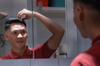 Banyodaki aynada saç yapan yakışıklı adam.