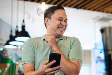 Yetişkin Adam Kafe 'de Rahat Bir Ayarda Akıllı Telefon İçeriğine Gülüyor