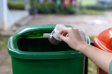 Plastik bardağı çöp kutusuna atmak, atık öğütme konsepti..