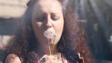 Woman Joy with Dandelions. Flying seeds and sunlight. Lovely Summer Mood. Fun with Dandelion seeds