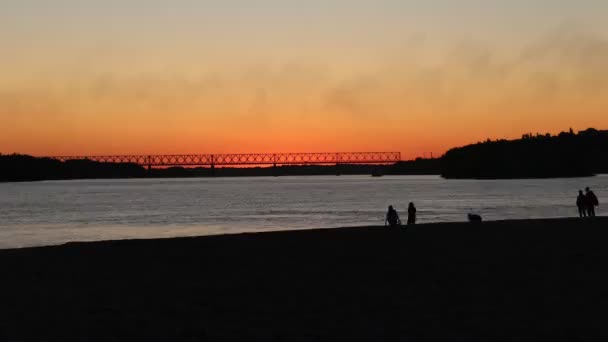 美丽的日落在海滩上 黑色的人物形象 一个人在海滩上行走的轮廓 海滩上的落日和人们的轮廓 晚上和夏天 假期时间 积极的人 — 图库视频影像
