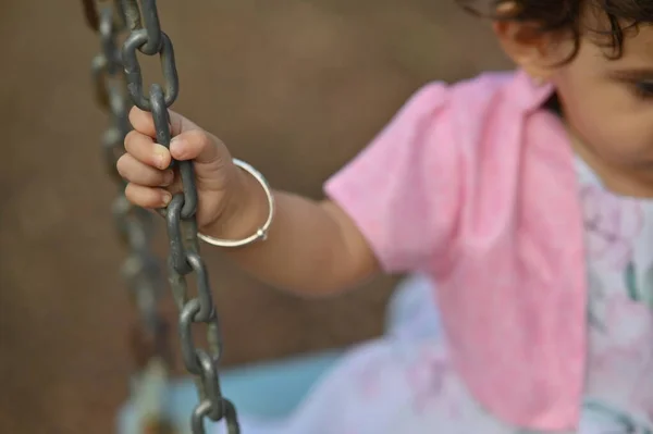 荡秋千的时候小手握住链条摆动 印度女婴 粉红衣服的女孩 小女孩在秋千上 — 图库照片