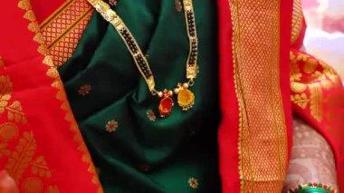 Altın Mangalsutra gerdanlığı yeşil sarinin üzerinde. Kutsal ipliğin seremonisi. Mangalsutra mücevherleri. Mangalsutra ile düğün ibadeti. Maharashtra. Hint Düğün Ritüelleri