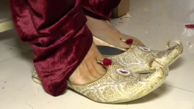 Geleneksel düğün ayakkabılarını giyen Hintli damat. Damat giyinme anı. Hint düğün anları