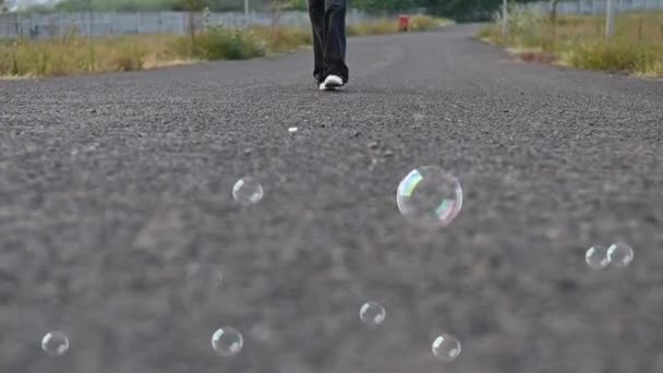 女人走路的腿飞行的肥皂泡 走在柏油路上 夏天的季节旅行夏天 思考的时刻 — 图库视频影像