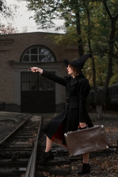 망토를 모자를 가방을 지팡이를 마녀가 기차역에서 요술쟁이들을 만난다 수직적 — 스톡 사진